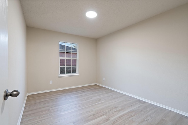 empty room featuring light hardwood / wood-style floors and a textured ceiling