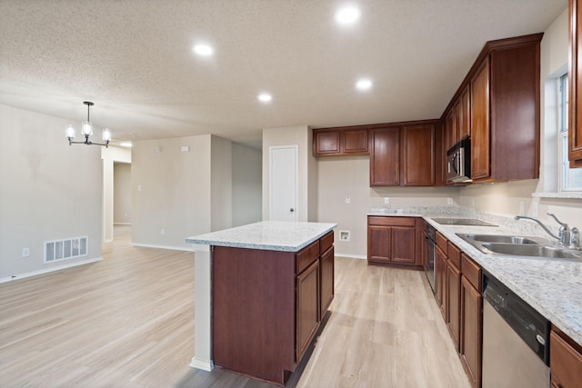 kitchen featuring light stone counters, sink, decorative light fixtures, and stainless steel appliances