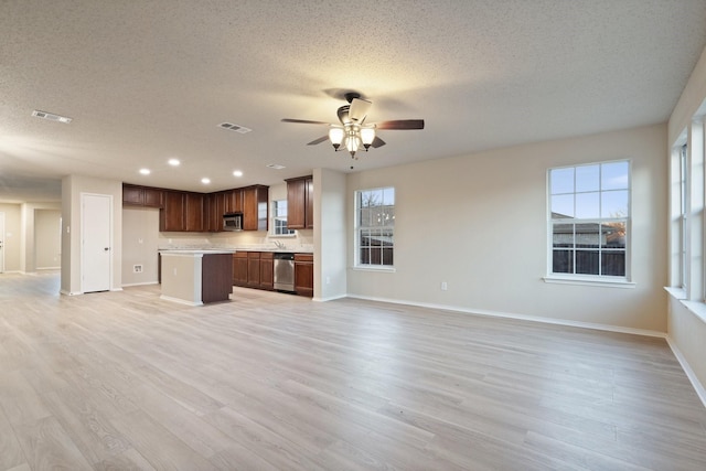 kitchen with a kitchen island, ceiling fan, stainless steel appliances, a textured ceiling, and light hardwood / wood-style flooring