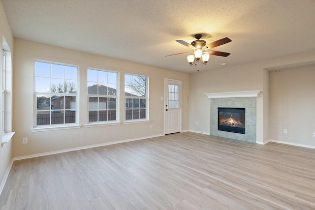 unfurnished living room with ceiling fan, a textured ceiling, a fireplace, and light hardwood / wood-style flooring