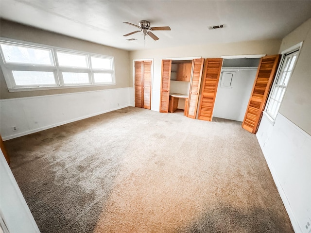 unfurnished bedroom featuring multiple closets, carpet, and ceiling fan