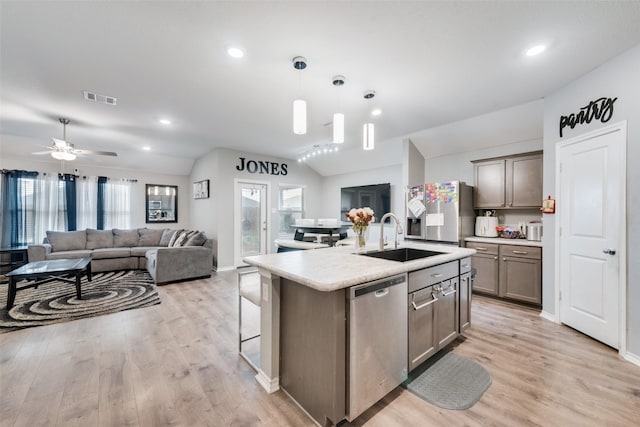 kitchen with appliances with stainless steel finishes, pendant lighting, lofted ceiling, sink, and a kitchen island with sink