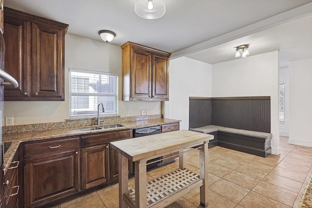 kitchen featuring sink, stone countertops, dark brown cabinets, light tile patterned floors, and dishwasher