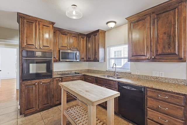 kitchen featuring light stone countertops, sink, light tile patterned floors, and black appliances