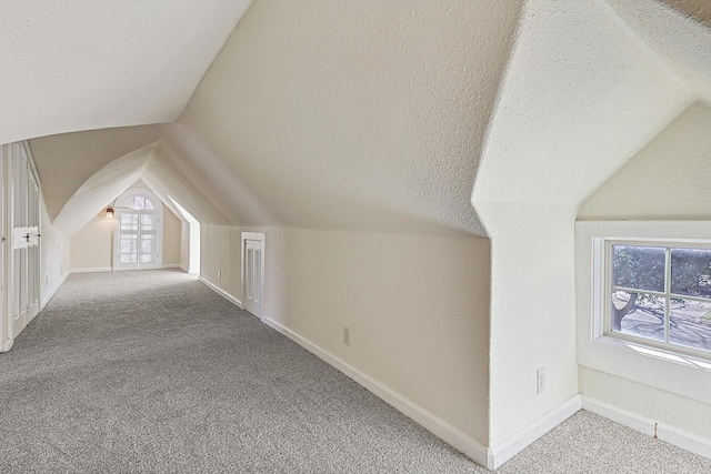 bonus room with lofted ceiling, carpet floors, and a textured ceiling