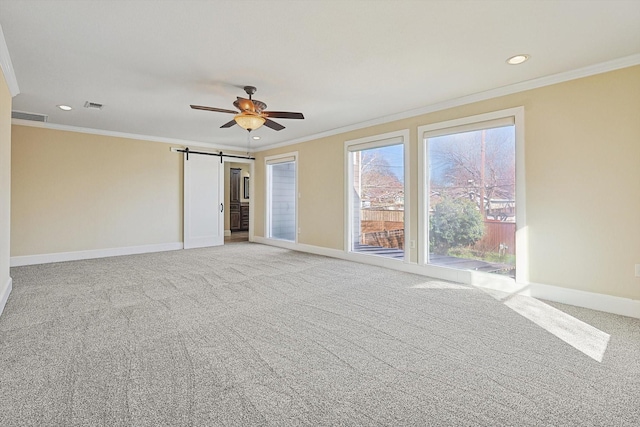 carpeted spare room featuring crown molding, ceiling fan, and a barn door