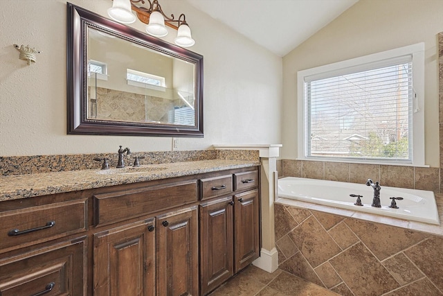 bathroom featuring vanity, tiled bath, and vaulted ceiling