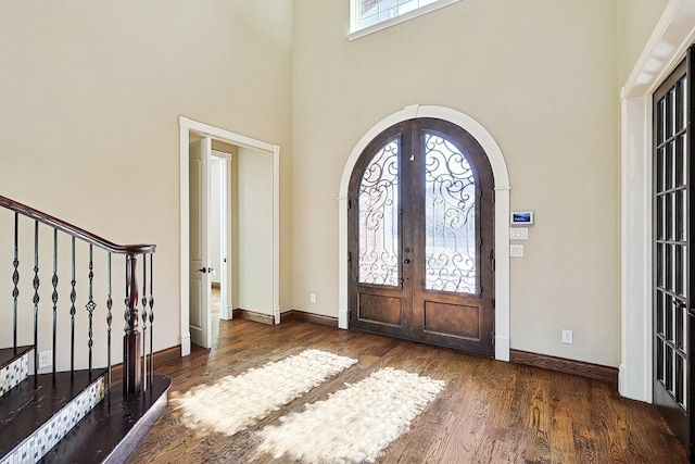 entrance foyer with dark hardwood / wood-style floors, french doors, and a high ceiling