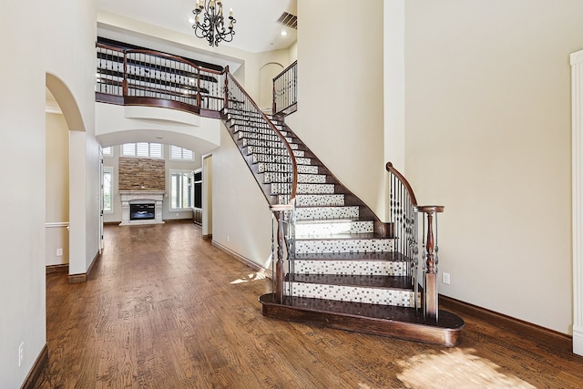 stairs featuring an inviting chandelier, a towering ceiling, and wood-type flooring