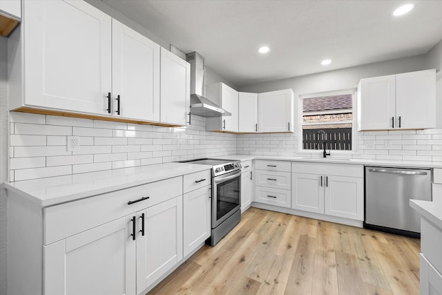 kitchen featuring white cabinetry, appliances with stainless steel finishes, sink, and wall chimney range hood