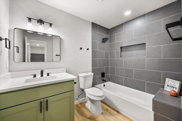 full bath featuring a textured wall, toilet, wood finished floors, tub / shower combination, and vanity