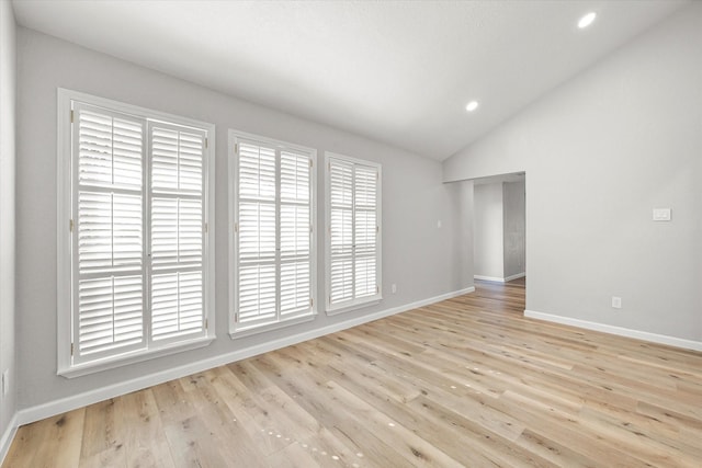 spare room featuring lofted ceiling and light hardwood / wood-style flooring