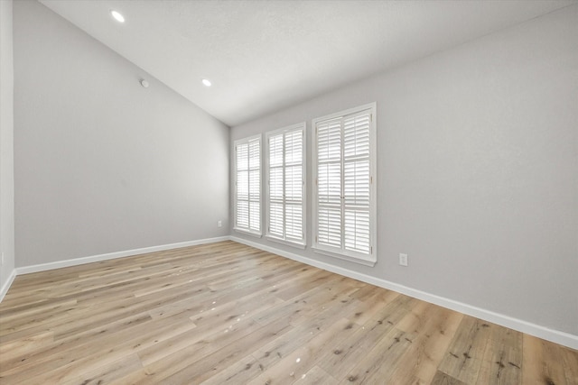 spare room featuring lofted ceiling and light hardwood / wood-style flooring