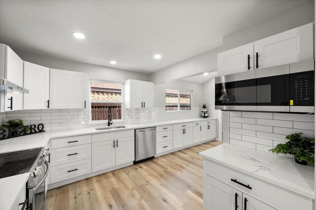 kitchen with white cabinetry, backsplash, and light hardwood / wood-style flooring