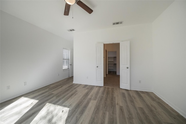 unfurnished bedroom with hardwood / wood-style flooring, ceiling fan, and a spacious closet