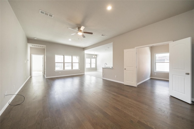 empty room with dark wood-type flooring, a wealth of natural light, and ceiling fan