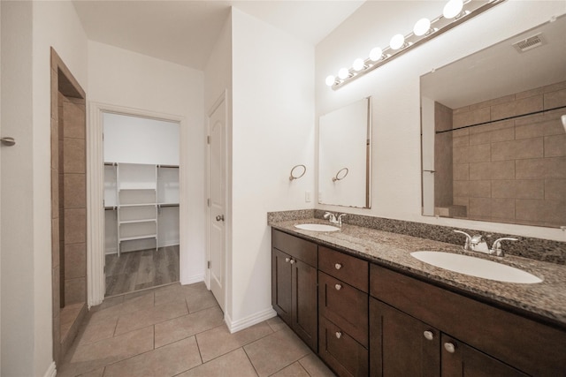 bathroom featuring vanity, tile patterned flooring, and a tile shower