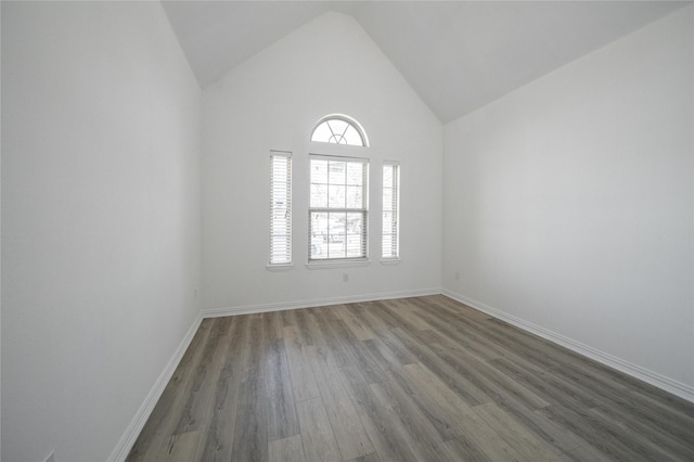 spare room featuring high vaulted ceiling and dark hardwood / wood-style flooring