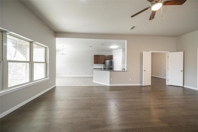 unfurnished living room featuring dark hardwood / wood-style flooring and ceiling fan with notable chandelier