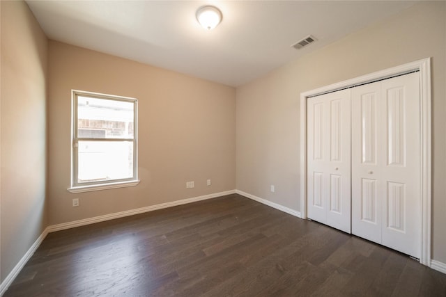 unfurnished bedroom with dark hardwood / wood-style floors and a closet