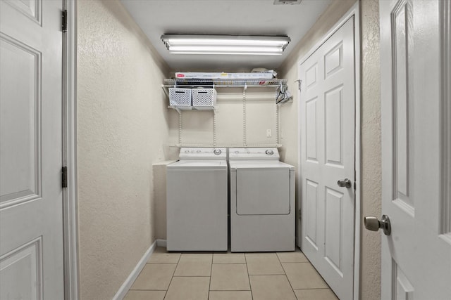 clothes washing area with light tile patterned flooring and washer and dryer