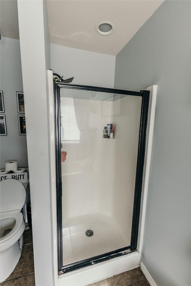 bathroom with tile patterned flooring, a shower with door, and toilet