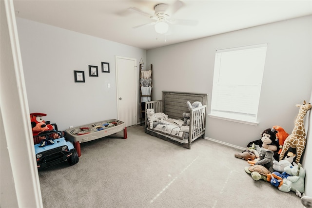 bedroom with light carpet, a crib, and ceiling fan