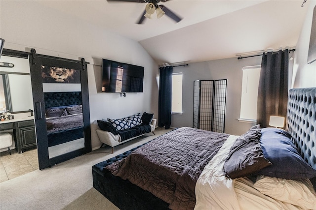 bedroom with ceiling fan, a barn door, vaulted ceiling, and light carpet