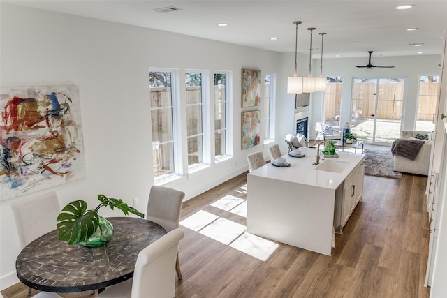 kitchen with sink, decorative light fixtures, light hardwood / wood-style floors, and a kitchen island