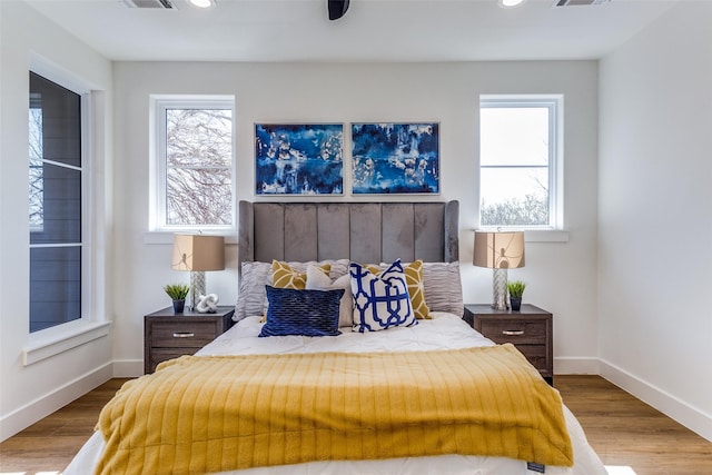 bedroom with multiple windows and hardwood / wood-style flooring