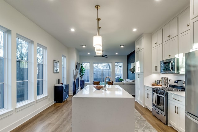 kitchen featuring appliances with stainless steel finishes, sink, a kitchen island with sink, and white cabinets