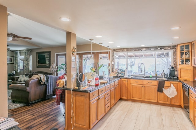 kitchen with sink, ceiling fan, black dishwasher, kitchen peninsula, and dark stone counters