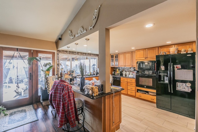 kitchen with a kitchen bar, tasteful backsplash, pendant lighting, light hardwood / wood-style floors, and black appliances