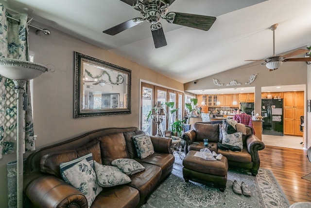 living room with ceiling fan, lofted ceiling, and hardwood / wood-style floors