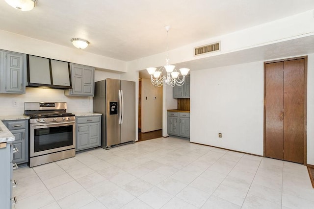 kitchen featuring gray cabinetry, a notable chandelier, pendant lighting, stainless steel appliances, and decorative backsplash