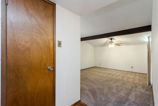 interior space featuring beamed ceiling, ceiling fan, and light carpet