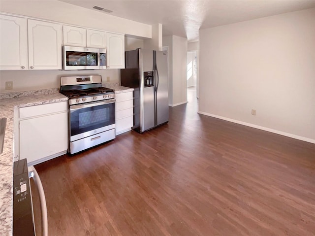 kitchen with light stone countertops, white cabinetry, appliances with stainless steel finishes, and dark wood-type flooring