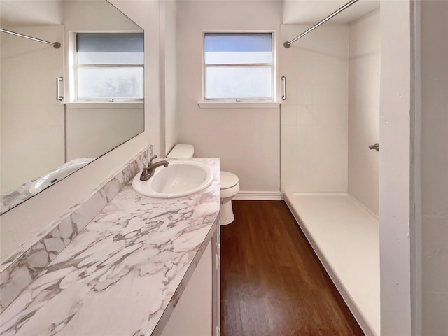 bathroom featuring vanity, hardwood / wood-style floors, walk in shower, and toilet