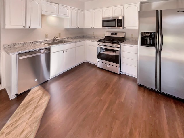 kitchen with sink, appliances with stainless steel finishes, white cabinetry, dark hardwood / wood-style floors, and light stone countertops