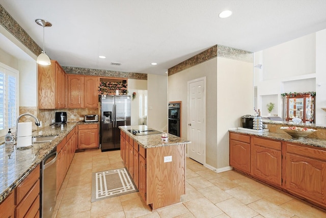 kitchen featuring sink, hanging light fixtures, a center island, light stone counters, and black appliances