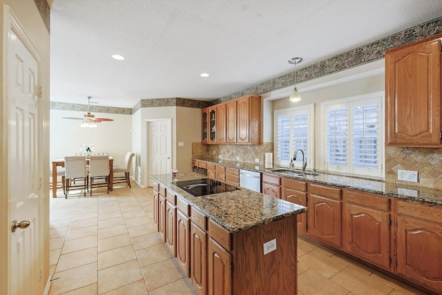 kitchen with sink, dark stone countertops, hanging light fixtures, a center island, and stainless steel dishwasher