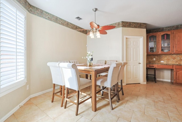 tiled dining room featuring ceiling fan and built in desk