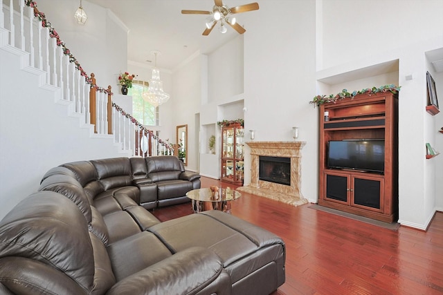 living room with built in shelves, dark hardwood / wood-style floors, ceiling fan, a fireplace, and a high ceiling