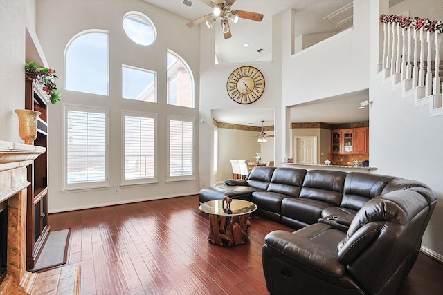 living room featuring dark hardwood / wood-style flooring, a premium fireplace, and ceiling fan