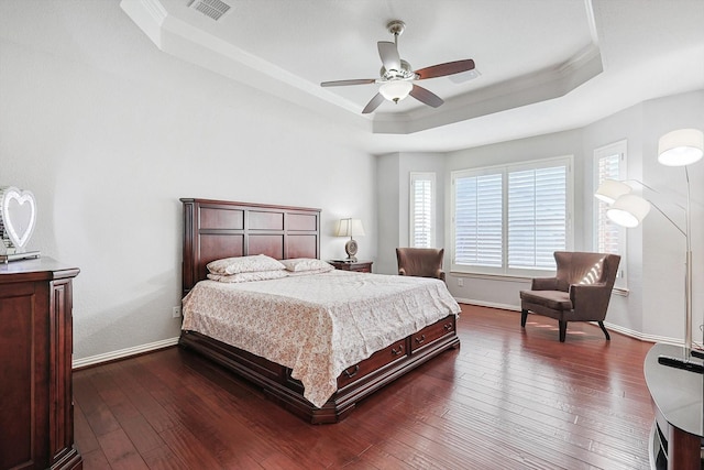 bedroom with ornamental molding, dark hardwood / wood-style floors, ceiling fan, and a tray ceiling