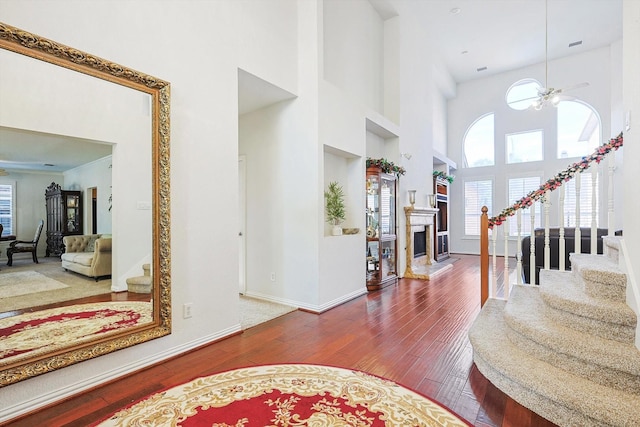 foyer featuring ceiling fan, wood-type flooring, and a high ceiling