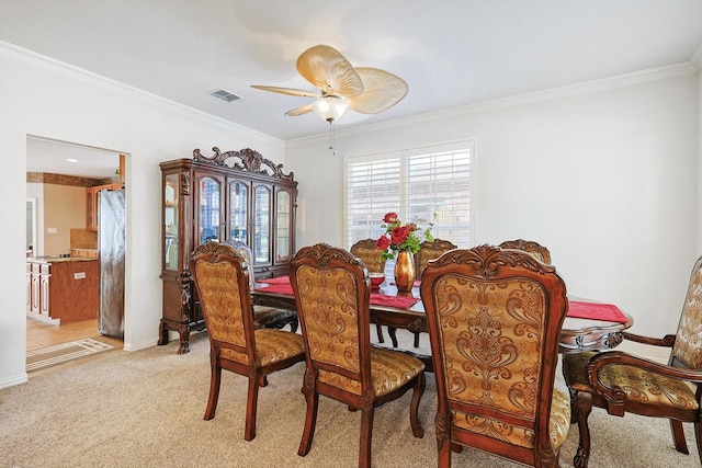 carpeted dining room with ceiling fan and ornamental molding