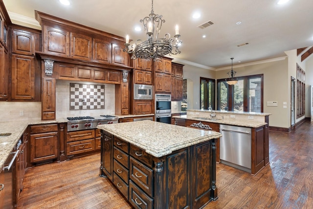 kitchen featuring a kitchen island, sink, hanging light fixtures, light stone counters, and stainless steel appliances