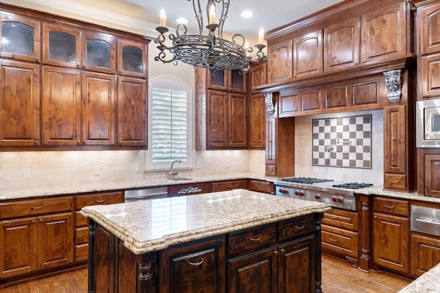 kitchen with a center island, appliances with stainless steel finishes, light stone countertops, and backsplash