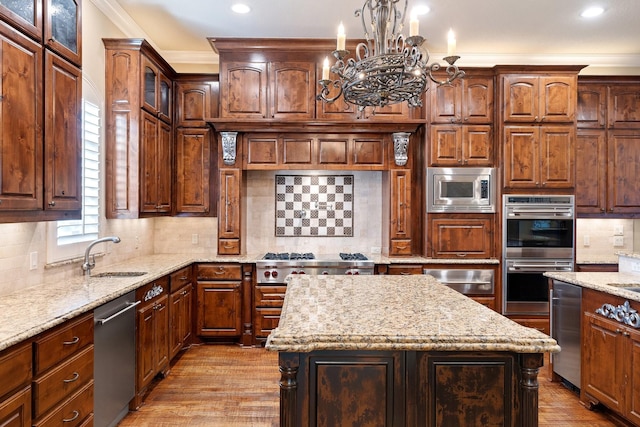 kitchen featuring sink, light stone counters, ornamental molding, appliances with stainless steel finishes, and a kitchen island